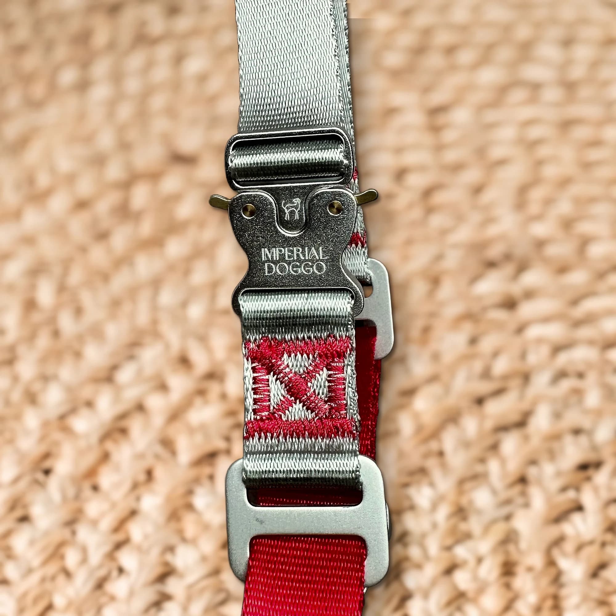 The aluminium cobra buckle, engraved with the Imperial Doggo hound and wordmark, above the red stitched mark