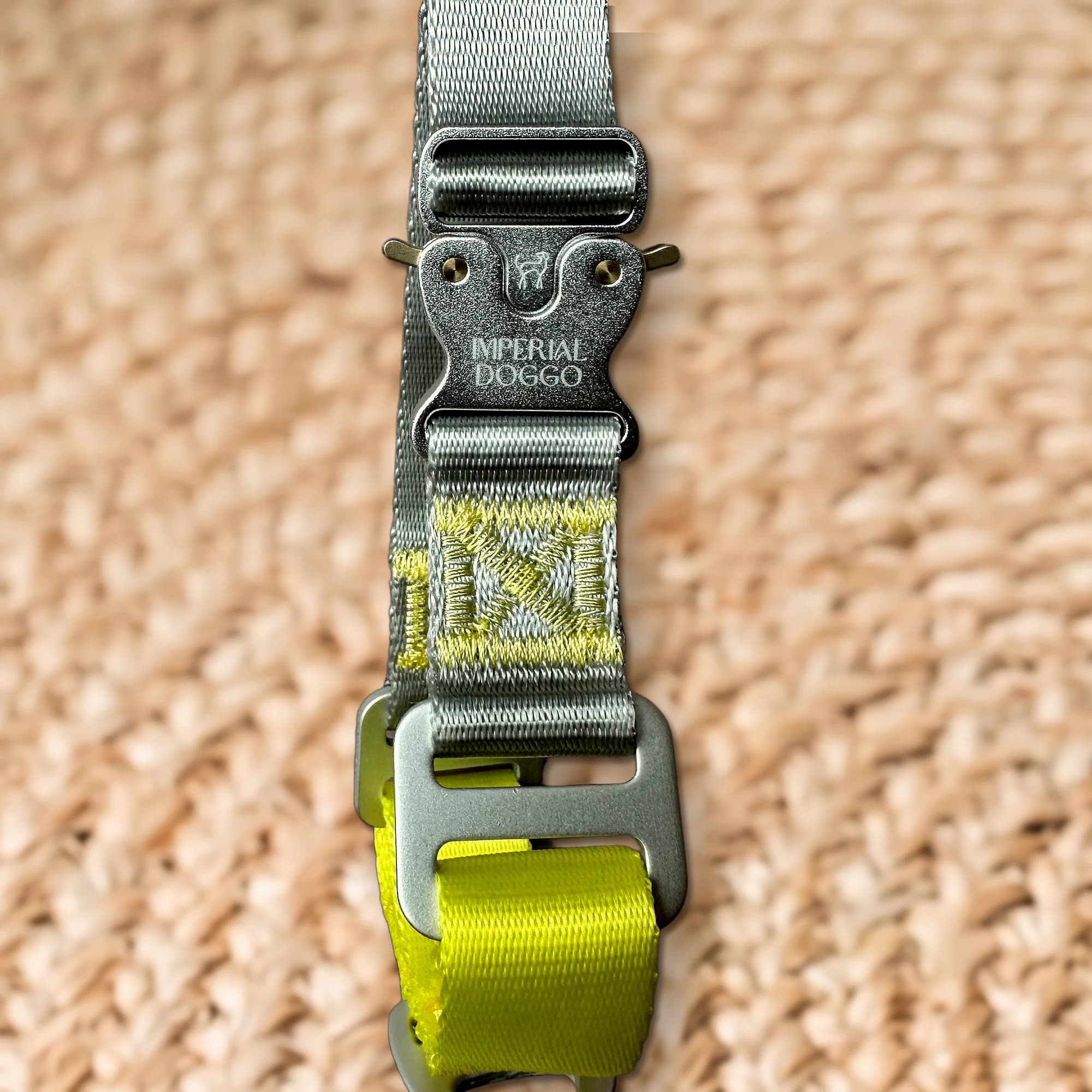 The aluminium cobra buckle, engraved with the Imperial Doggo hound and wordmark, above the yellow stitched mark